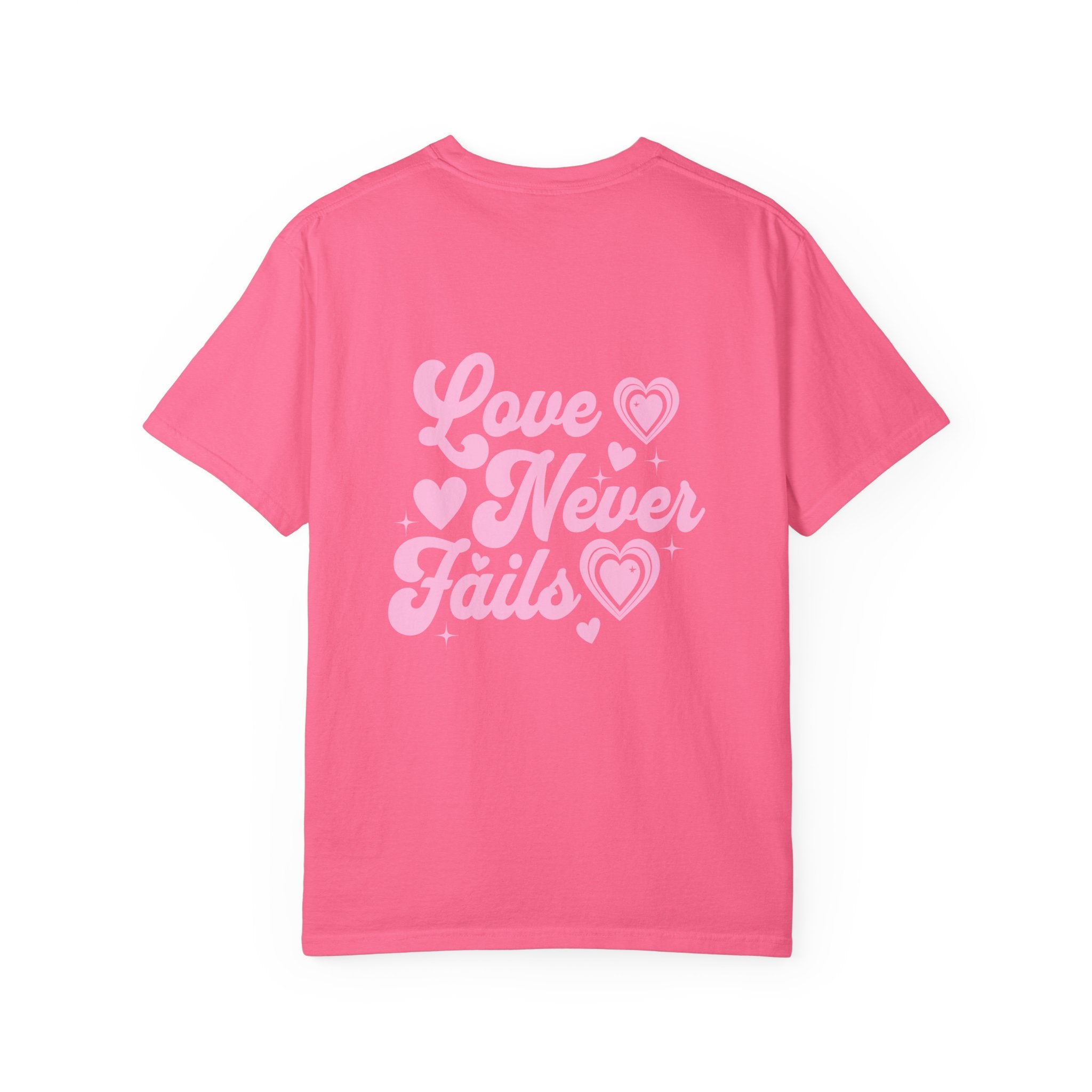 Pink t-shirt with 'Love Never Fails' text on a white background