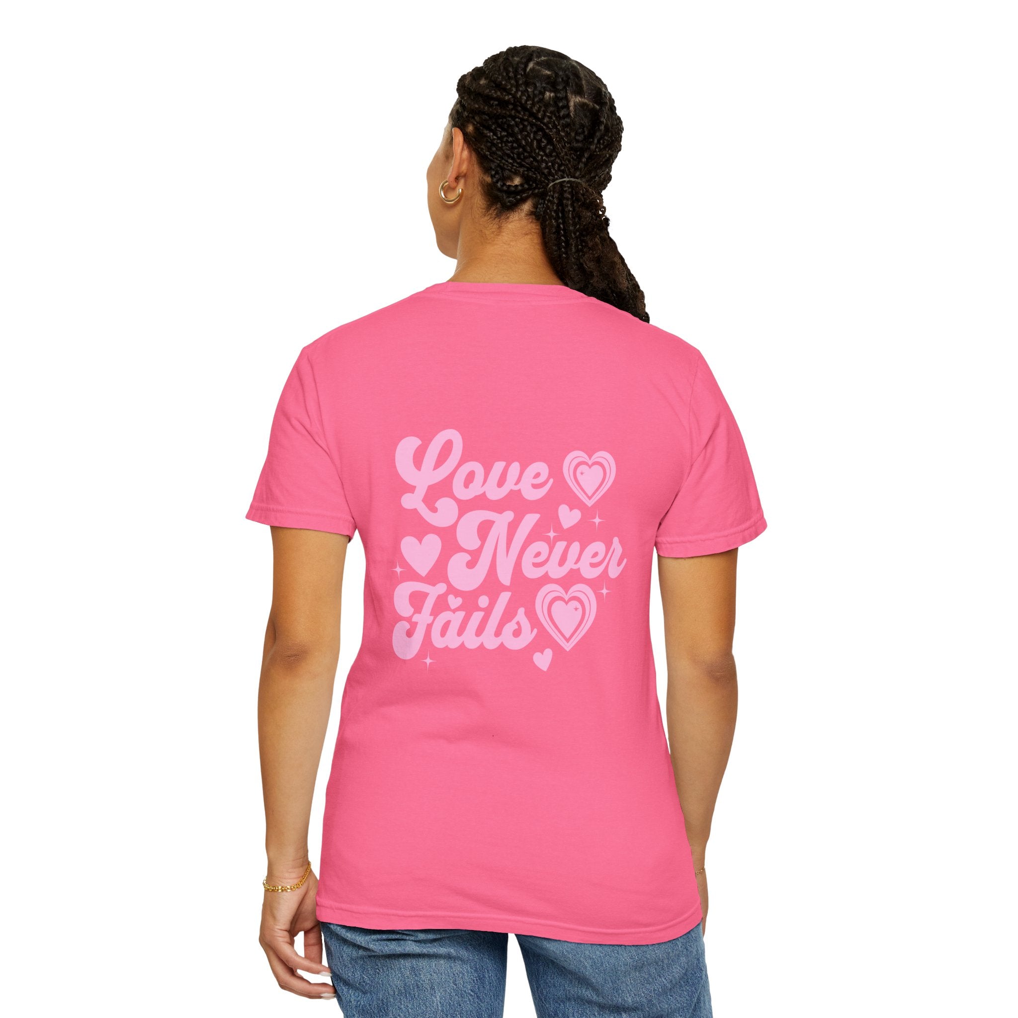 Person wearing a pink t-shirt with 'Love Never Fails' text on the back