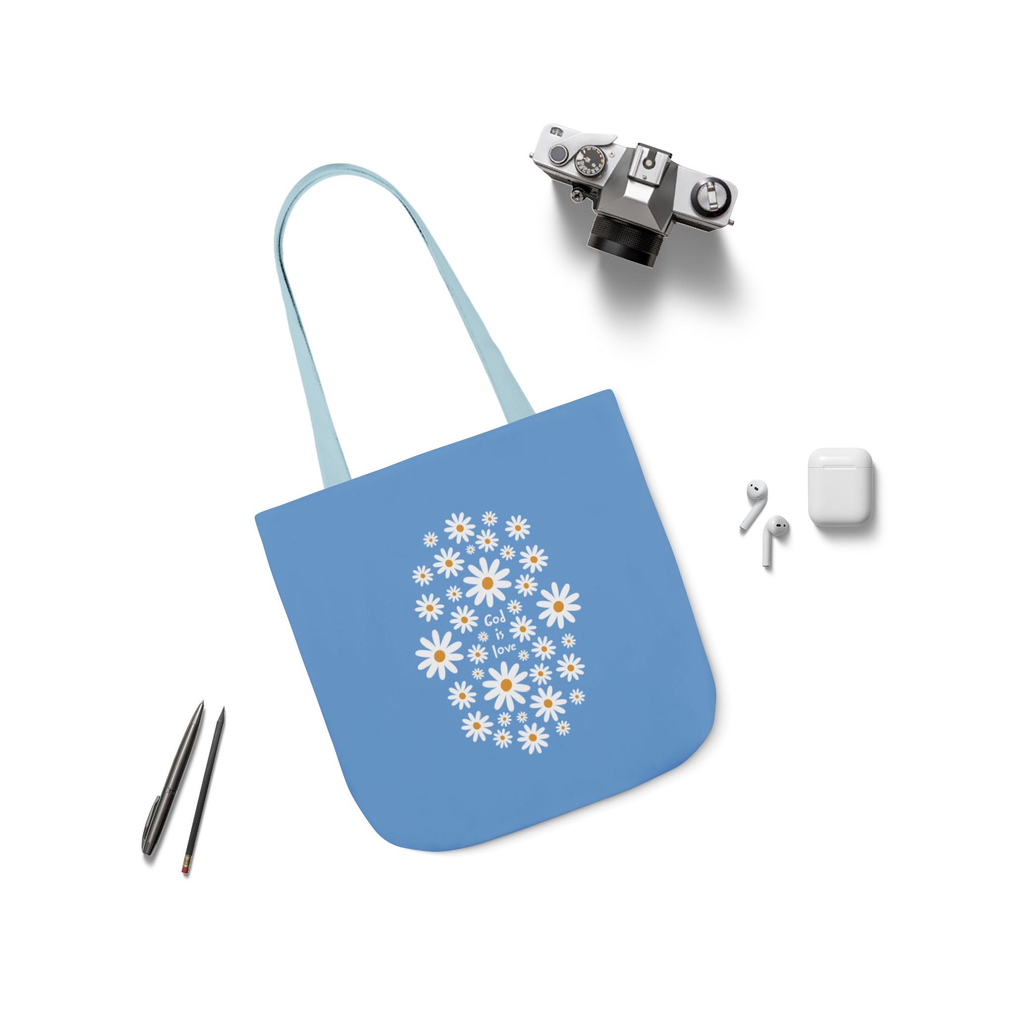 Blue tote bag with floral design, camera, pen, and earbuds on a white background