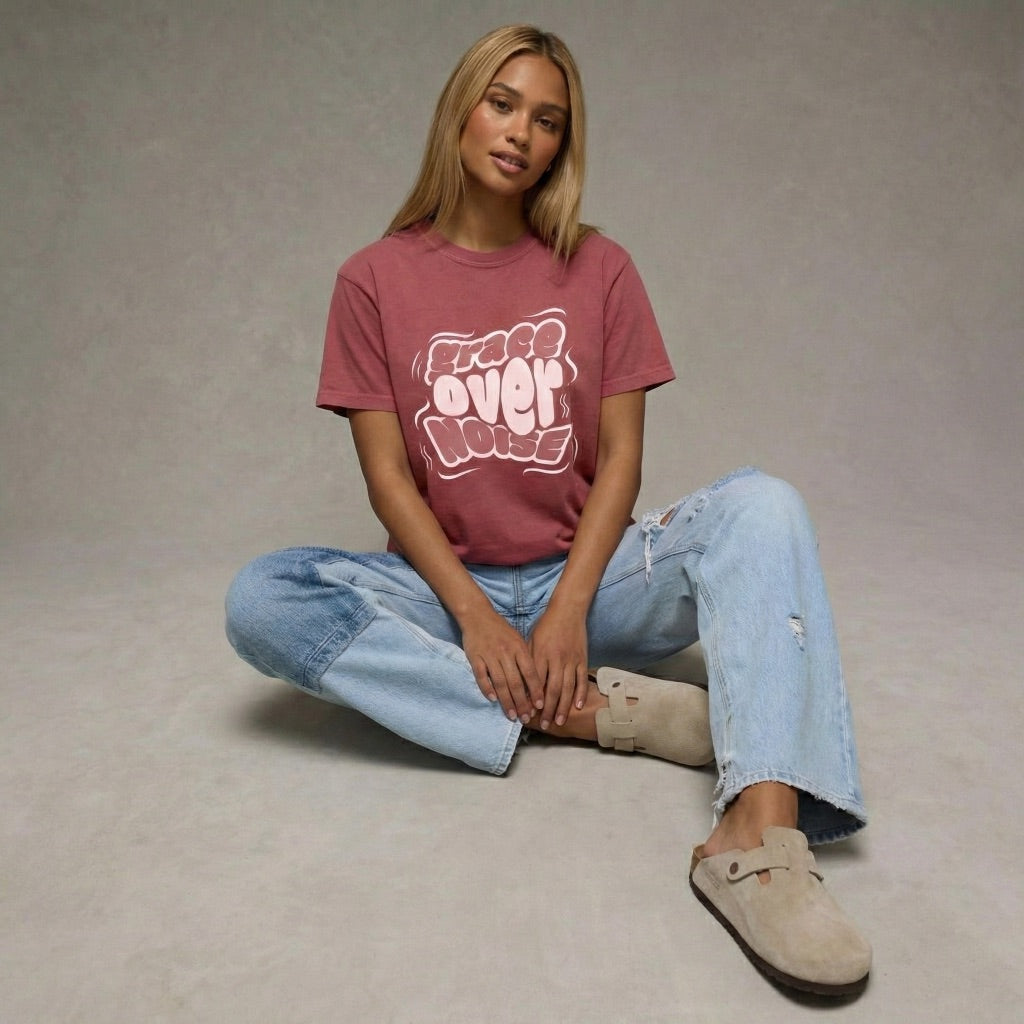 Woman wearing a maroon Grace Over Noise unisex t-shirt with white bubbly streetwear typography by Way Is Made 3