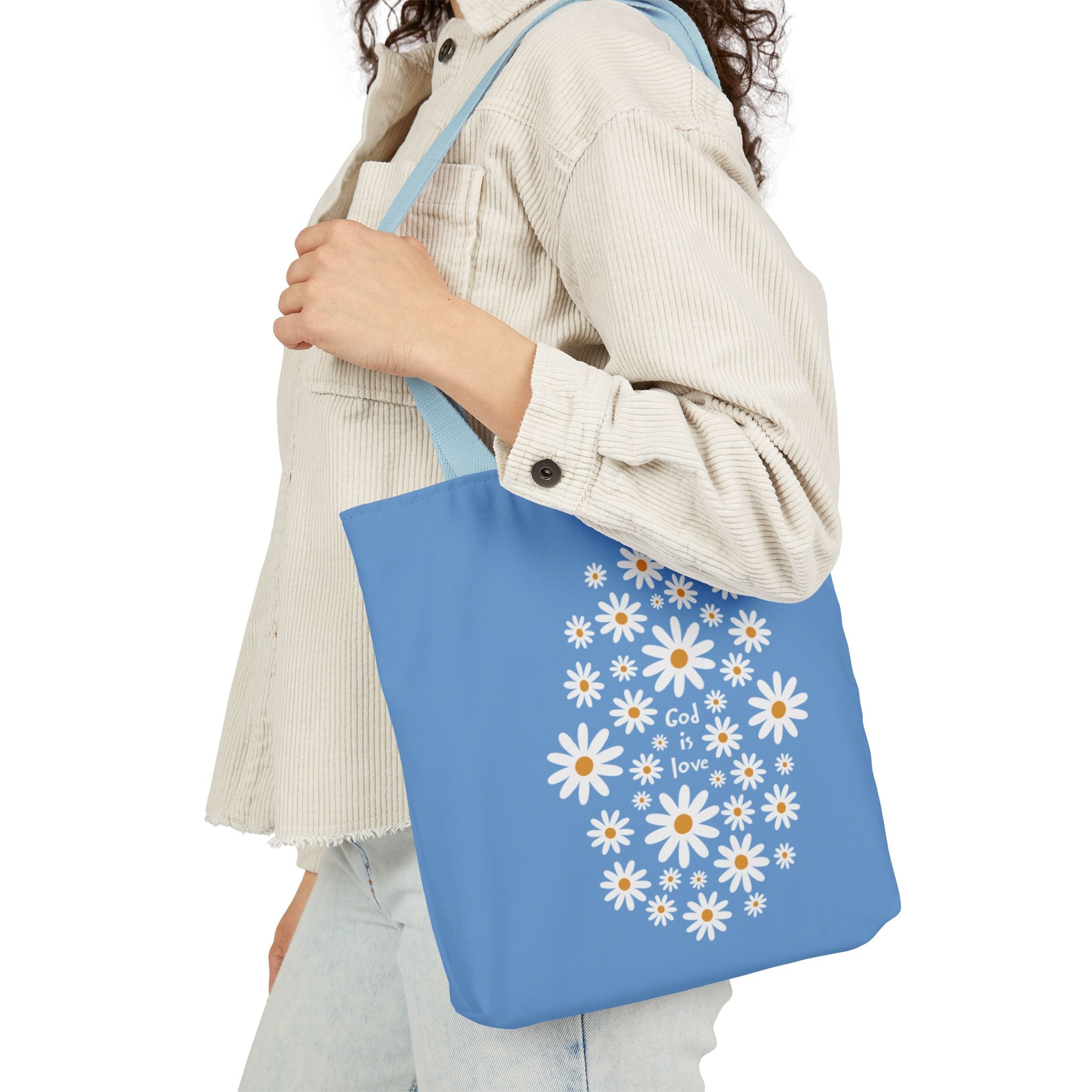 Person holding a blue tote bag with floral design and text.