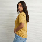Model wearing gold New Every Morning unisex tshirt with pink retro graphic