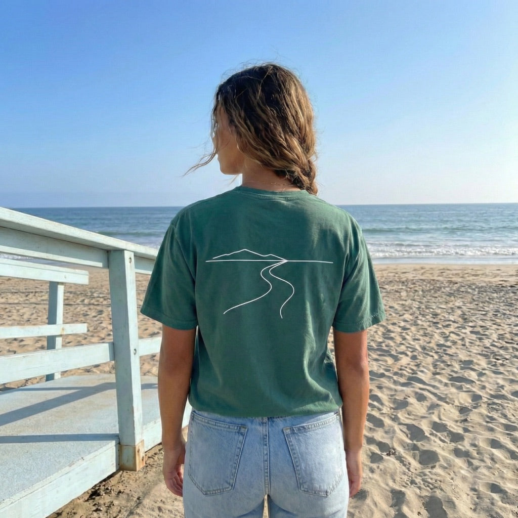 Close up of front pocket print on teal On The Way t-shirt featuring white script text.