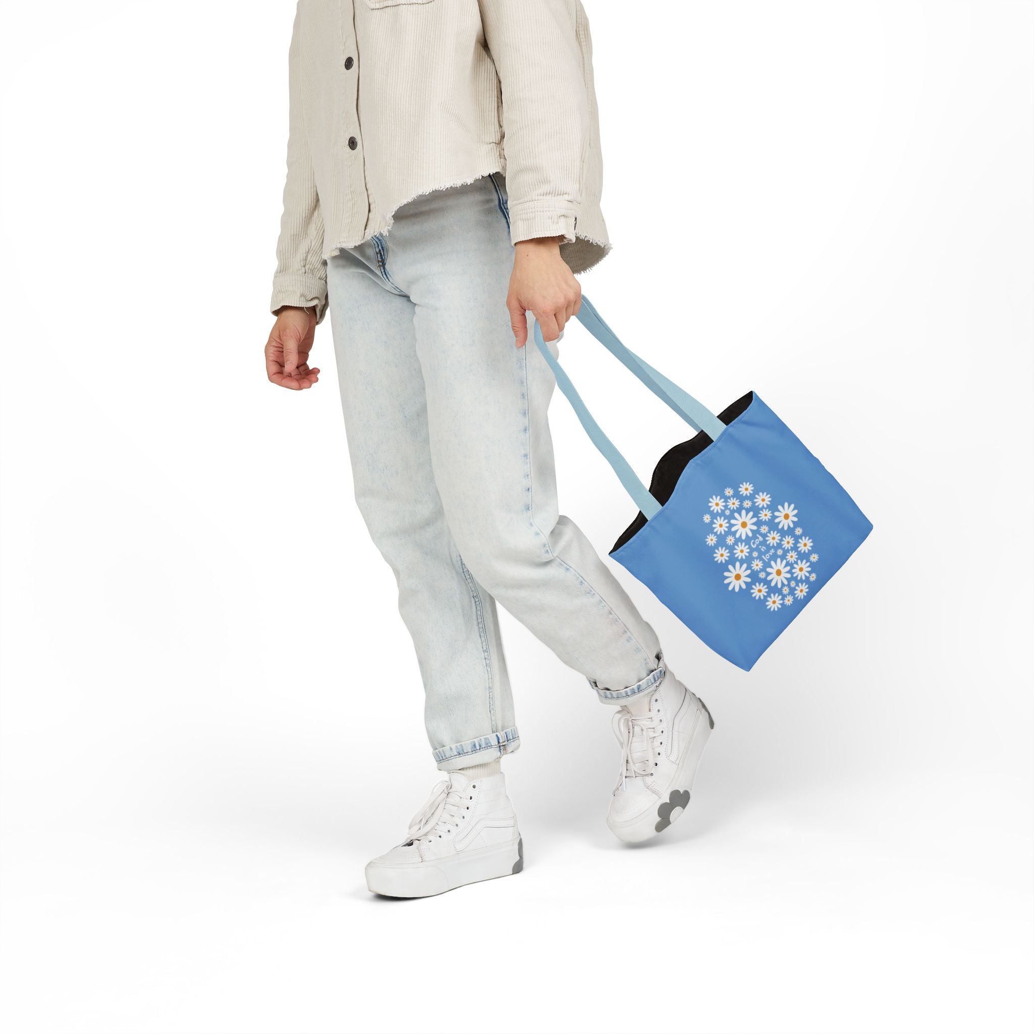 Person holding a blue tote bag with floral design on a white background