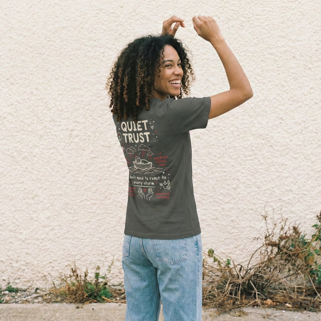 Man wearing charcoal Quiet Trust graphic tee with vintage hand-drawn faith-based illustrations and red accents